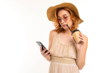 Beyaz arka planda cep telefonuyla poz veren genç kadın.  