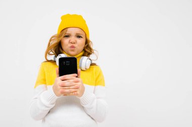 Stüdyoda kulaklık ve cep telefonuyla poz veren hoş bir kız. 