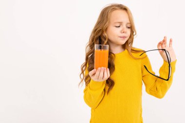 Stüdyoda hafif arka planda meyve suyu ile poz veren tatlı kız. 