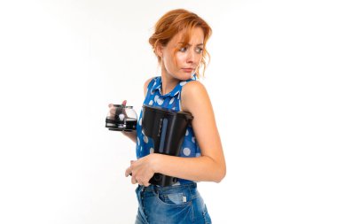 Genç kızıl saçlı kadın kahve makinesinin beyaz arka planında poz veriyor.  