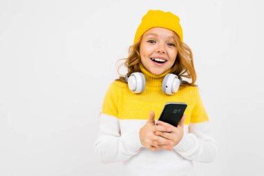 Stüdyoda kulaklık ve cep telefonuyla poz veren hoş bir kız. 