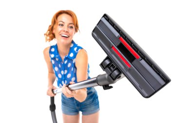 Genç kızıl saçlı kadın elektrik süpürgesi beyaz arka planda poz veriyor.  