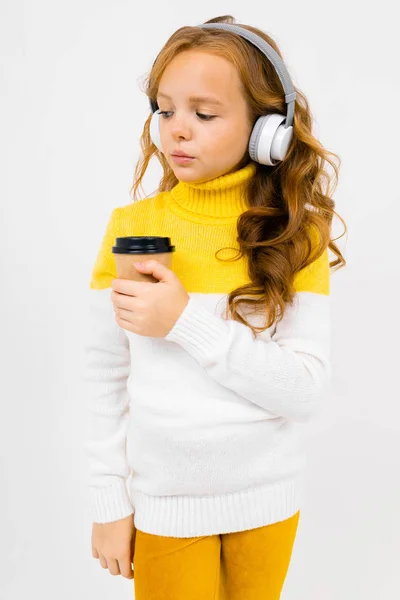 Cute Little Girl Słuchawki Pozowanie Papierowym Kubkiem Studio Jasnym Tle — Zdjęcie stockowe