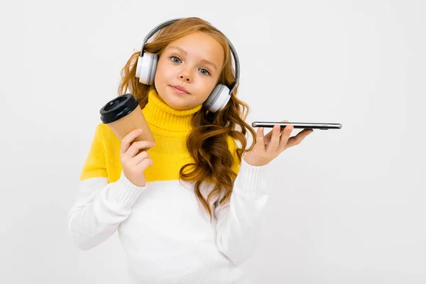 Cute Little Girl Słuchawki Pozowanie Papierowym Kubkiem Telefon Komórkowy Studio — Zdjęcie stockowe