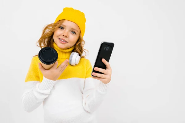 Cute Little Girl Słuchawki Pozowanie Papierowym Kubkiem Telefon Komórkowy Studio — Zdjęcie stockowe