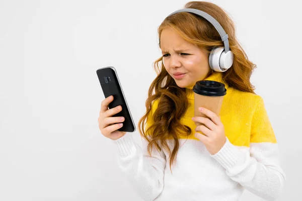 Cute Little Girl Słuchawki Pozowanie Papierowym Kubkiem Telefon Komórkowy Studio — Zdjęcie stockowe