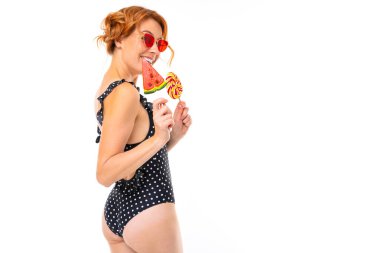 Güneş gözlüklü genç kadın beyaz arka planda şekerlerle poz veriyor.  