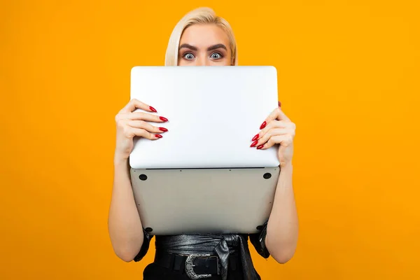 Fată blondă fermecătoare a comandat cursuri de educație online cu un laptop în mâinile ei pe un fundal studio galben — Fotografie, imagine de stoc