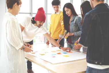 Çok ırklı yaratıcı ekip birlikte çalışıyor, toplantı yapıyor ve iş yerindeki masada beyin fırtınası yapıyor. Başlangıç çeşitliliği takım çalışması beyin fırtınası toplantısı ve masa başı konsepti üzerine notlar