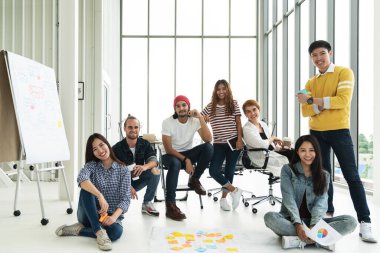 Modern ofiste konuşan, gülen ve beyin fırtınası yapan çok ırklı genç bir grup. 