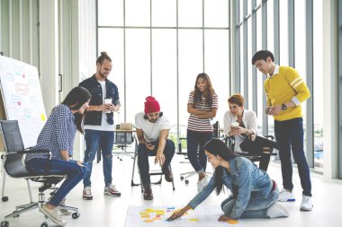 Modern ofiste konuşan, gülen ve beyin fırtınası yapan çok ırklı genç bir grup. 