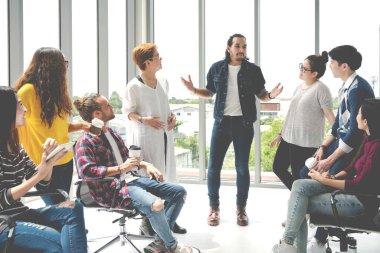 Ofiste kahve molasında rahatlama bölgesinde konuşan çekici, çok ırklı genç bir grup. Genç Asyalı hippi, iş yerinde eğlenceli ve mutlu arkadaşlarla yaşam tarzı fikrini paylaşıyor..