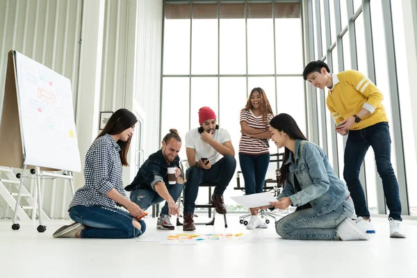 Modern ofiste konuşan, gülen ve beyin fırtınası yapan çok ırklı genç bir grup. 