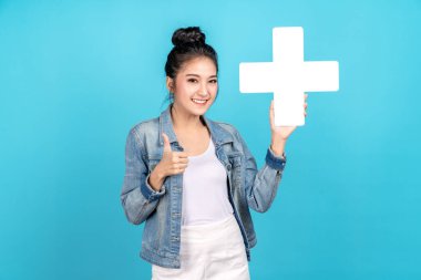 Mutluluk Asyalı kadın gülümsüyor, artı ya da ekliyor işaret ve baş parmak yukarı ya da mavi arka plan gibi. Hoş Asyalı kız, günlük kot pantolon giyiyor ve daha yoğun ve daha yararlı bir konsept için işaret veriyor.