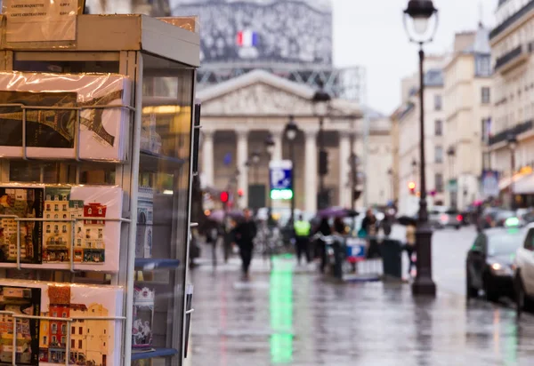 Şehrin turistik manzaraya: Paris Pantheon Hediyelik eşya ile yakınındaki alışveriş ön plan ve bulanık Pantheon, sokak, kartpostal ile bina, arabalar ve yapılar bir arka plan olarak.