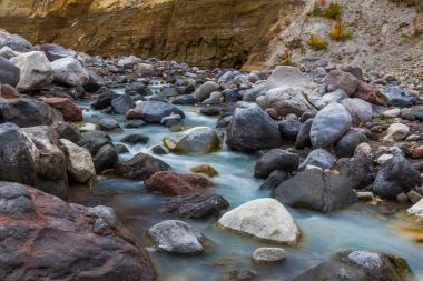 Dağ dere tarafından taşlar ve kayalar tarafından çevrili bir sonbahar.