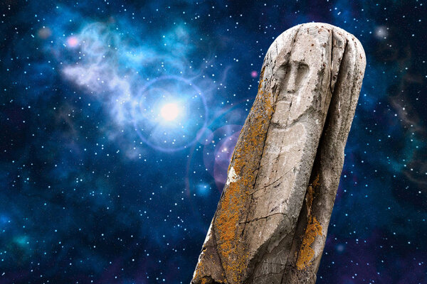 Ancient stone ritual idol (totem) with a universe image - space, stars, nebula, supernova explosion - as a background.
