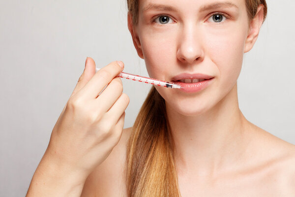 Attractive woman plastic surgery with syringe in her face