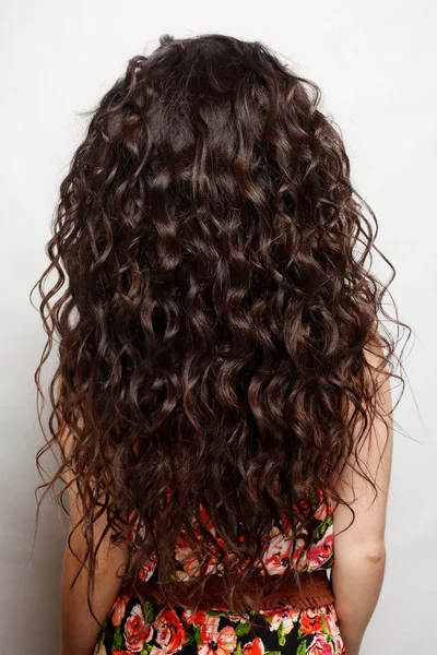 Tył kobiety z długimi brązowymi kręconymi włosami — Zdjęcie stockowe
