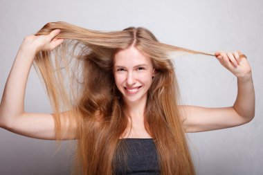 uzun saçlı esmer kameraya gülümseyen.