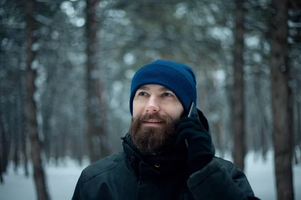 Красивый бородач зимой делает селфи в лесу. — стоковое фото