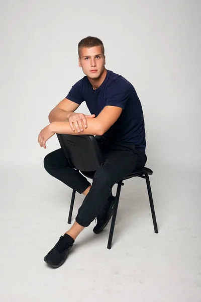Joven hombre de la moda sentado en una silla — Foto de Stock
