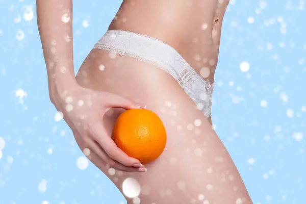 Hermosa figura femenina con una naranja sostiene cerca del culo —  Fotos de Stock