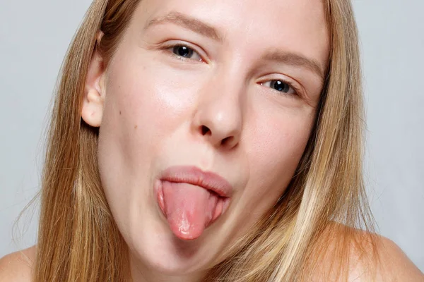 Joven bonita mujer dispara la lengua, aislado en gris — Foto de Stock