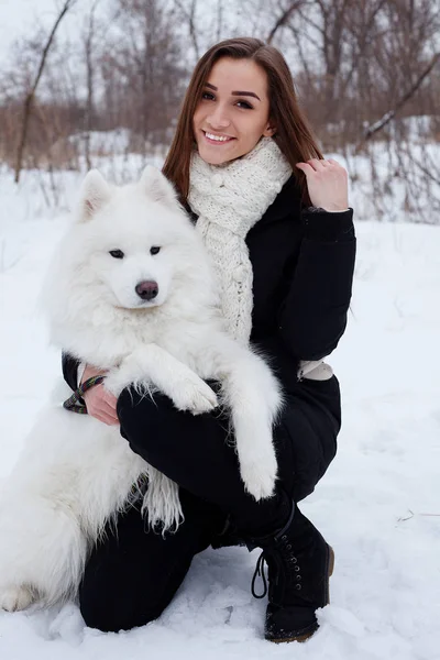 Kobieta właściciel pieszczoty Ogarnięcie biały samojeda psa na śniegu — Zdjęcie stockowe