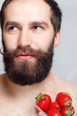 çilek tutarak ve gülümseyen yakın çekim portre genç adam