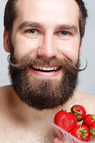 Крупным планом портрет молодого человека, держащего клубнику и улыбающегося — стоковое фото