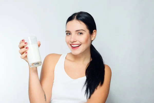 Latte Donna che beve latte, felice e sorridente bella giovane donna che si gode un latte di vetro — Foto Stock