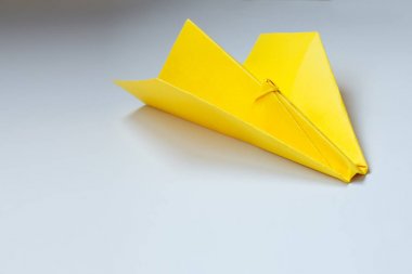 Beyaz zemin üzerine sarı origami uçak.