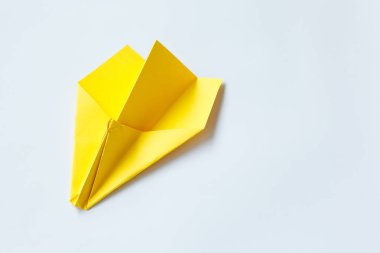 Beyaz zemin üzerine sarı origami uçak.