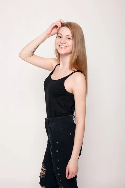 Mode junge Frau lächelt, schaut verwirrt in die Kamera auf grauem Hintergrund — Stockfoto