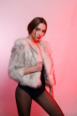 Moda güzel kadın yapay kürk kırmızı bir arka plan üzerinde gri kürk paltolu çatık durumda