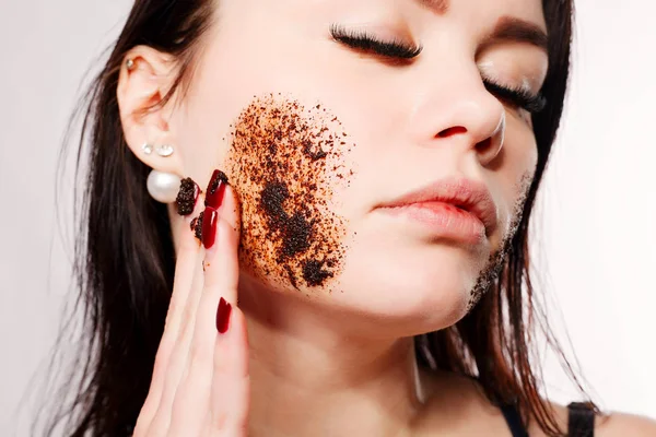 Brunette cleanses the skin with coffee scrub — Stock Photo, Image