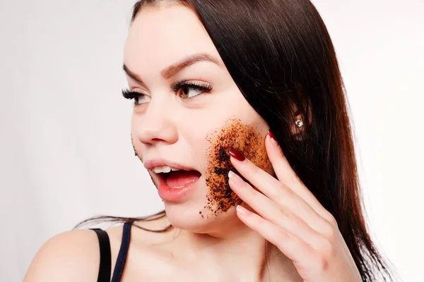 Brunette cleanses the skin with coffee scrub — Stock Photo, Image