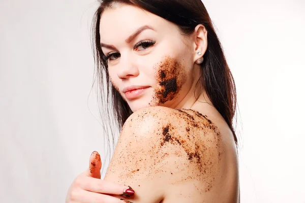 Mujer morena limpia la piel del exfoliante de café corporal — Foto de Stock