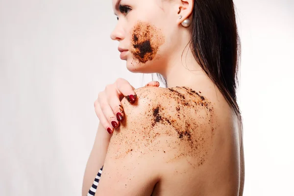 Mujer morena limpia la piel del exfoliante de café corporal — Foto de Stock