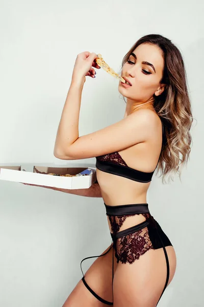 Młoda sexy kobieta w czarnej underweartasty kawałek pizzy — Zdjęcie stockowe