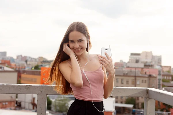 Mladá žena se sluchátky na její mobilní telefon — Stock fotografie