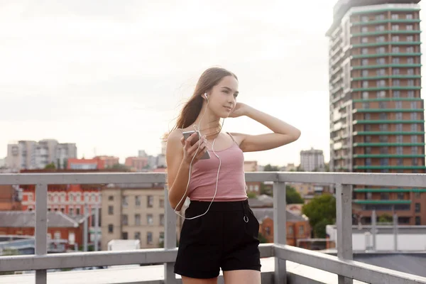 Mujer joven con auriculares colgando en su teléfono móvil — Foto de Stock