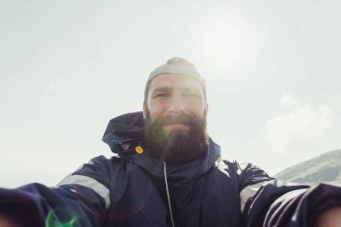 Genç adam Gezgin Selfie arka plan dağlar üzerinde yapar