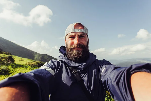 Genç adam Gezgin Selfie arka plan dağlar üzerinde yapar — Stok fotoğraf