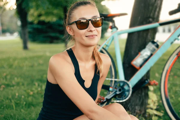 Chica sonriendo al lado de su bicicleta en el parque —  Fotos de Stock