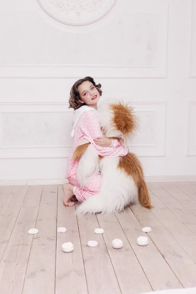 Cute little girl in pajama with sweets sitting on the floor