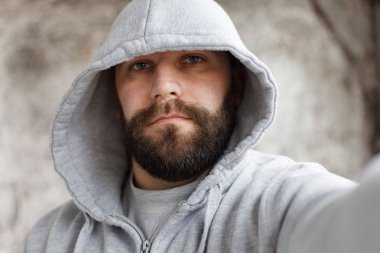 sakallı adam gri bir arka plan üzerine bir selfi yapar