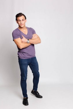 Gri arka plandaki yakışıklı genç adam kameraya bakıyor.