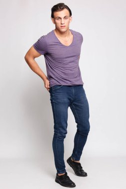 Gri arka plandaki yakışıklı genç adam kameraya bakıyor.